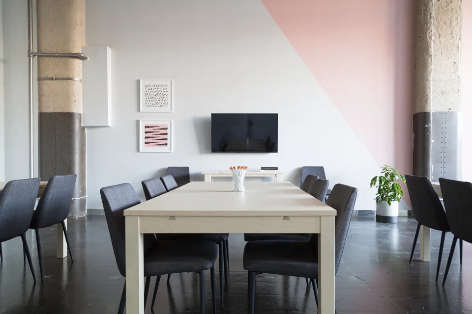 An empty meeting room with a table, chairs and wall-mounted screen