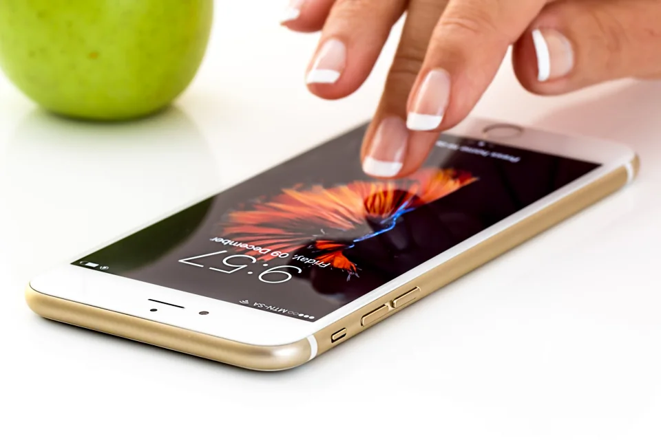 A hand using a smartphone on a desk